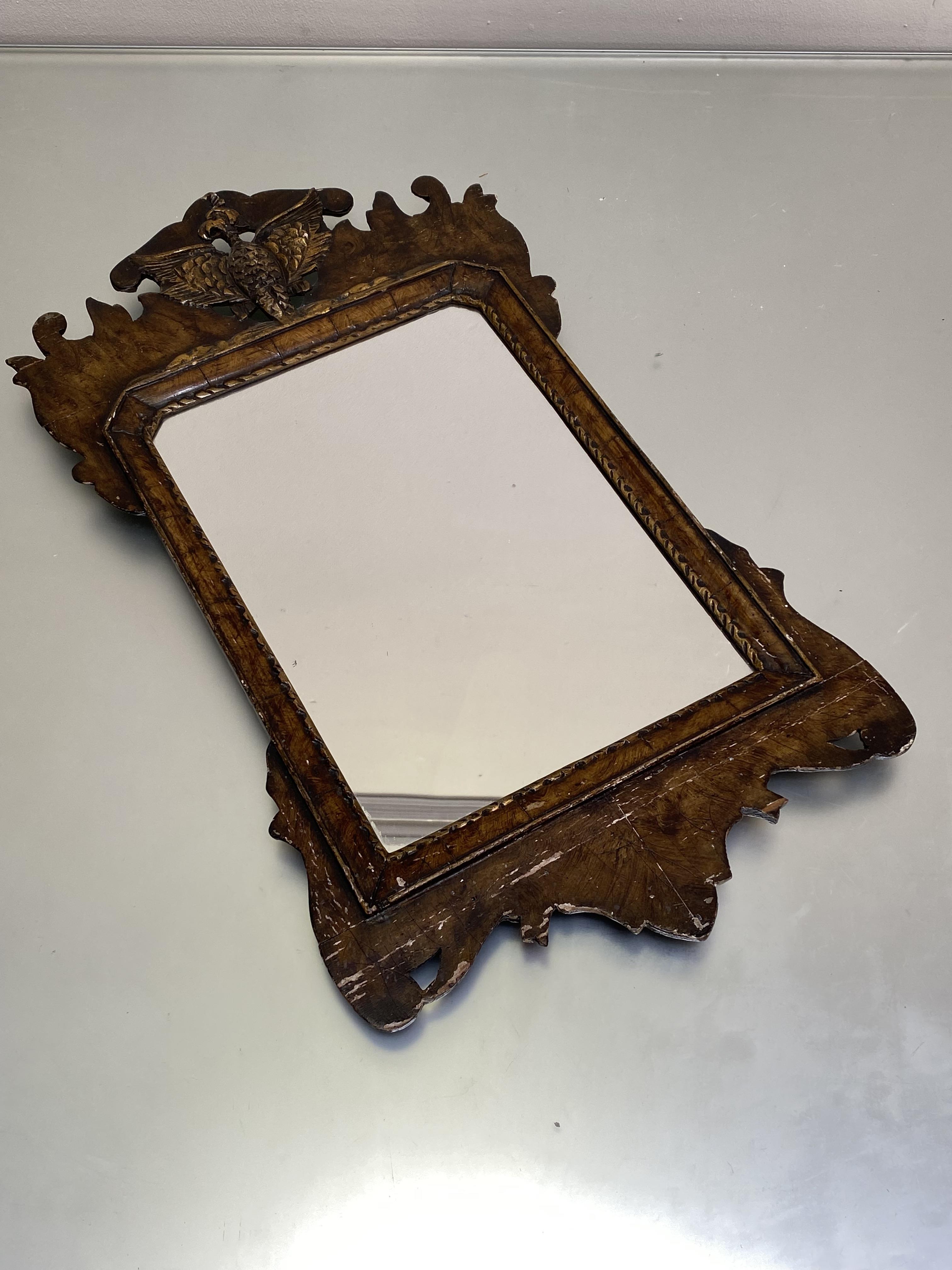 A grain-painted fretwork mirror, the shaped plate within a parcel-gilt cushion-moulded slip, the