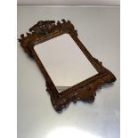 A grain-painted fretwork mirror, the shaped plate within a parcel-gilt cushion-moulded slip, the