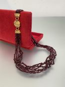 A late 19th century five-strand ruby bead necklace, the uniform strands on an unmarked engraved