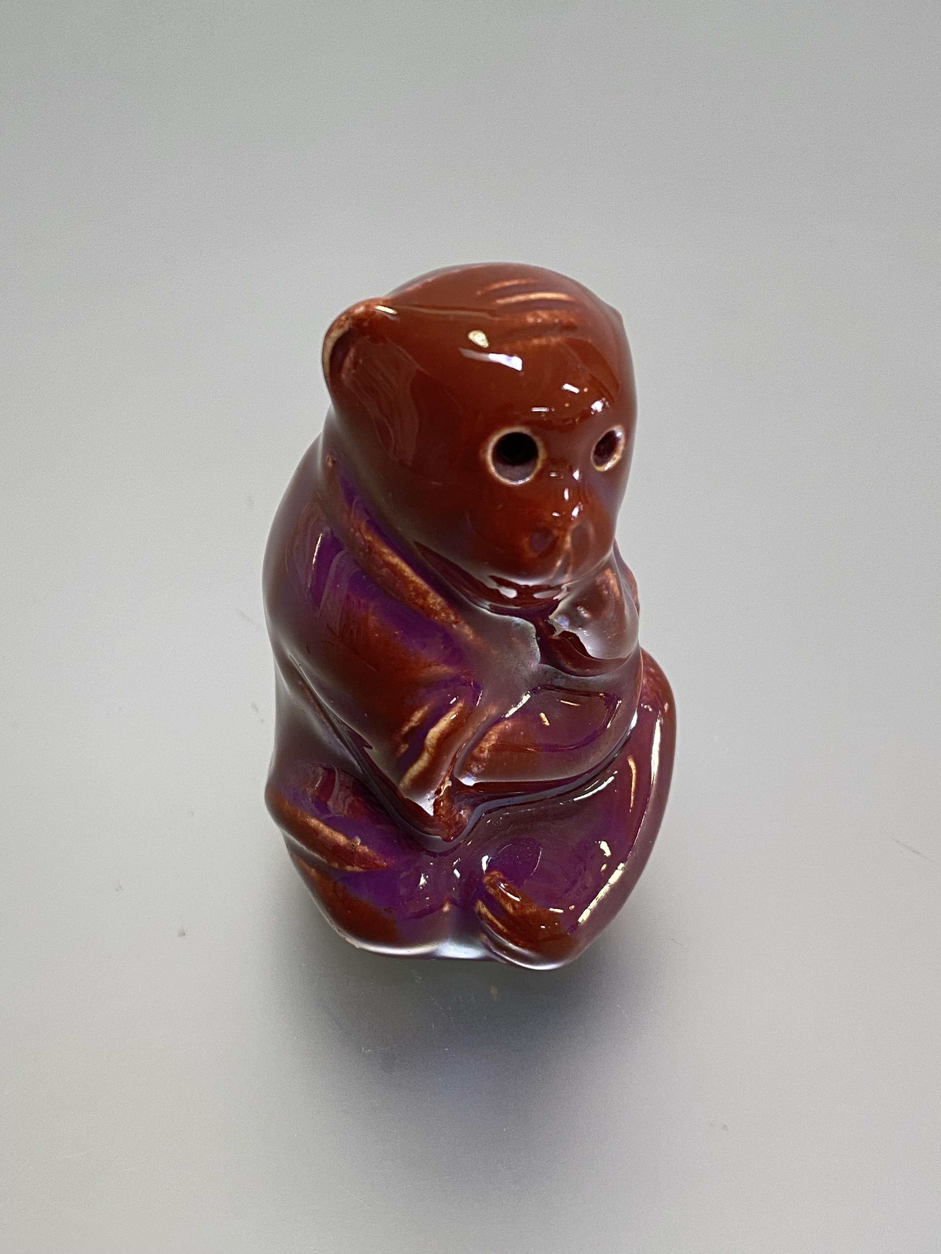 A Burmantofts Faience model of a seated monkey, in an oxblood glaze, incised no. 1996 and factory