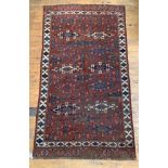 An antique Kazak rug, the red field of repeating geometric design framed within an ivory border with
