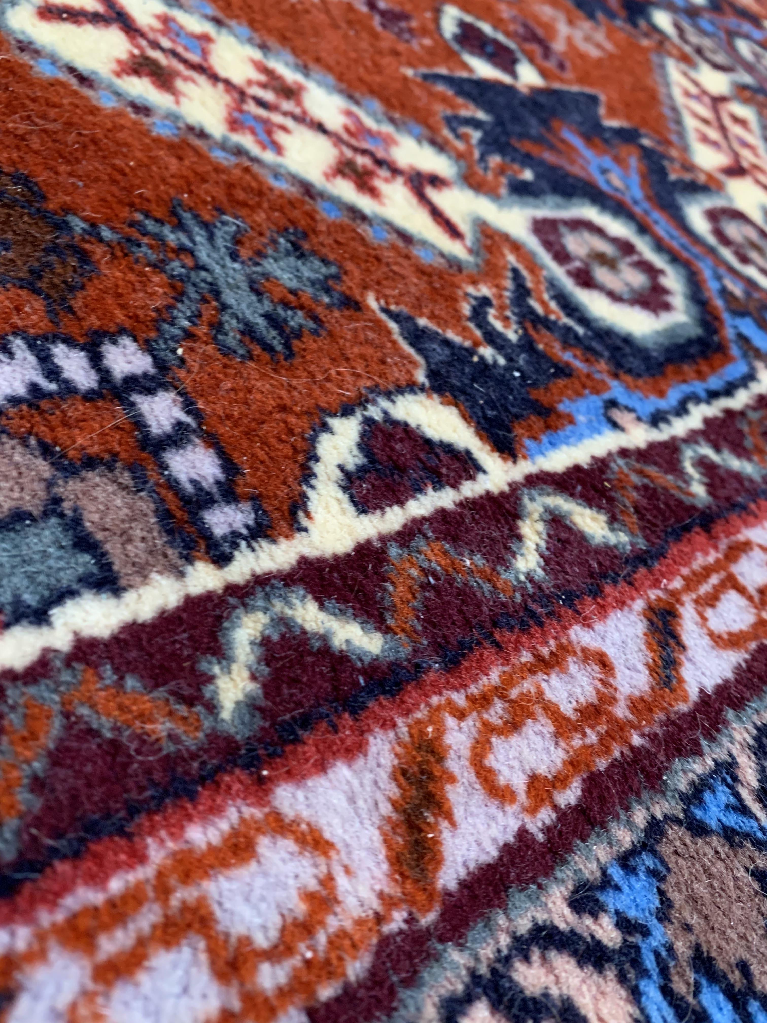 A hand knotted North West Persian rug, the madder ground of repeating design enclosed by double - Image 2 of 3
