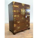 A Vietnamese brass bound stained hardwood cabinet on chest, the twin doors with brass strap hinges