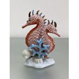 A Herend porcelain red fishnet model of a pair of seahorses with coral branches, printed marks.