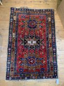 A hand knotted rug, the triple medallion on madder field and bordered, 195cm x 129cm