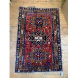 A hand knotted rug, the triple medallion on madder field and bordered, 195cm x 129cm