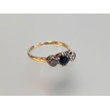 An 18ct gold three stone sapphire and diamond ring, the central round-cut sapphire claw-set