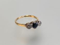 An 18ct gold three stone sapphire and diamond ring, the central round-cut sapphire claw-set