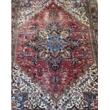 A hand knotted Persian Heriz carpet, the geometric medallion on a red field of all over stylised