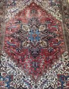 A hand knotted Persian Heriz carpet, the geometric medallion on a red field of all over stylised