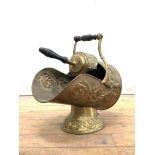 An Edwardian hammered brass coal scuttle of helmet form, worked in a floral design, with ring turned