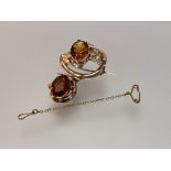 A late Victorian Cairngorm citrine brooch, the two oval-cut stones claw set in a leaf-modelled frame