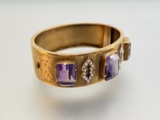A late 19th century amethyst and seed pearl set hinged cuff bangle, the three large graduated