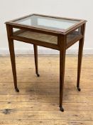 An Edwardian mahogany bijouterie table, with glazed hinged top above a glazed frieze, raised on