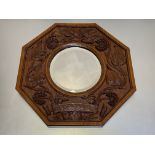 A German Arts & Crafts carved oak wall mirror, c. 1910, the bevelled circular mirror plate within an