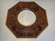 A German Arts & Crafts carved oak wall mirror, c. 1910, the bevelled circular mirror plate within an