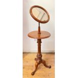 A mid-Victorian walnut shaving stand, the circular mirror plate within a conforming moulded frame,