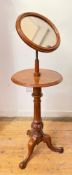 A mid-Victorian walnut shaving stand, the circular mirror plate within a conforming moulded frame,