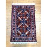 A hand knotted North West Persian rug, the madder ground of repeating design enclosed by double