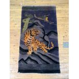 A Chinese washed wool rug, the deep purple field decorated with a tiger within a mountainous