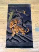 A Chinese washed wool rug, the deep purple field decorated with a tiger within a mountainous