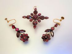 A floral cruciform garnet pendant, formed of round and pear-cut stones mounted in unmarked yellow