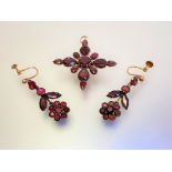 A floral cruciform garnet pendant, formed of round and pear-cut stones mounted in unmarked yellow