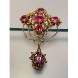 A Victorian yellow metal brooch set with pink stones, the navette-form scroll-cast upper section set