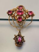 A Victorian yellow metal brooch set with pink stones, the navette-form scroll-cast upper section set