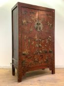 A Chinese red lacquered marriage cabinet, circa 1900, decorated with embossed gilt figures within