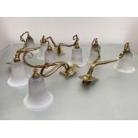 A set of four twin-light brass and opaque glass wall lights in Art Nouveau style, each shaped