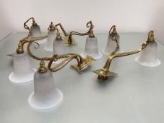 A set of four twin-light brass and opaque glass wall lights in Art Nouveau style, each shaped