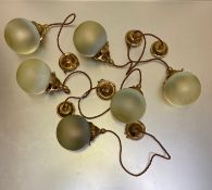 A set of six brass and vaseline glass pendant lights, each globe-form shade on a brass cap,
