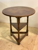 An 18th century design oak cricket table, circa 1930, the circular top above pegged ring turned