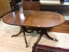 A walnut reproduction Regency style twin pedestal dining table, the tablet shaped top with an