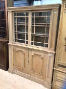 A 19thc stripped pine bookcase, the cushion cornice above two glazed doors enclosing two shelves,