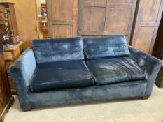 A contemporary three-seater sofa upholstered in blue velvet with slightly flared arm on squat