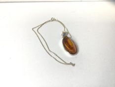 A polished amber pendant necklace on silver chain, measures 27cm
