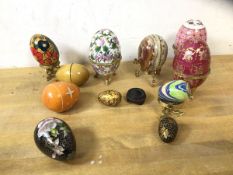 A group of egg ornaments including three hinged china boxes, each measuring 10cm high, polished