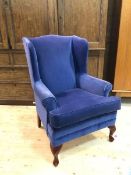 A Georgian inspired wingback arm chair with scrolled arms, seat cushion, on cabriole front supports,