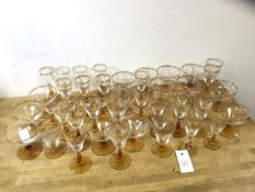 A quantity of stemware with gilt floral decoration to edges, on amber glass stems and bases,