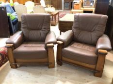 A pair of modern lounge armchairs with oak frames and chocolate brown leather back and seat cushions