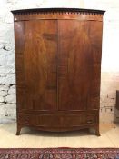 An Edwardian walnut bow front wardrobe, the dentil and arcaded cornice above a plain frieze and
