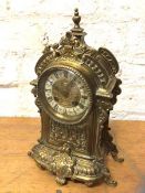 A late 19th early 20thc brass rococo inspired mantel clock, the enamel dial with roman numerals,