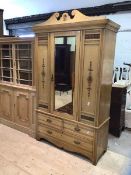 An Edwardian ash wardrobe, the swan neck pediment over bevelled mirror glazed door enclosing silk