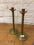 A pair of brass candlesticks with twisted stems on stepped circular bases having copper