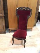 A late 19thc high back nursing chair with foliate moulding, red velvet upholstered back and seat, on
