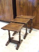 A set of three oak nesting tables on turned supports and trestle bases