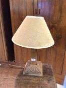 An oak table lamp with obelisk style stem on foliate carved base, having jute lined lampshade,