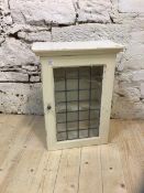 A 1920's / 30's bathroom cabinet, the moulded top over glazed and leaded door, interior with two
